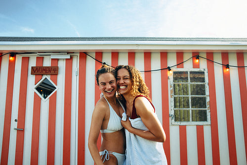 A beach scene with friends in swimwear captures sauna community and recovery