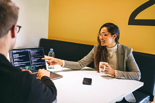Tech colleagues discussing software design and coding in a coworking office