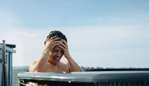 A man explores wellness through an outdoor ice bath under a blue sky.