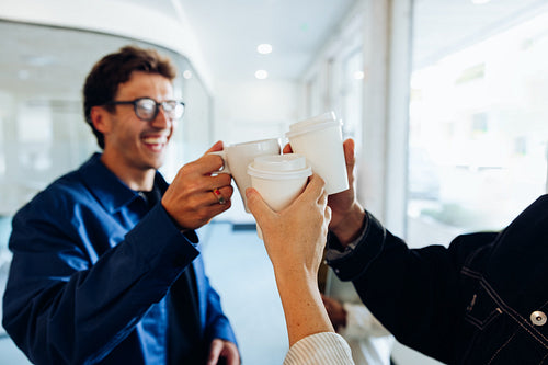Coworkers toast with coffee cups in office