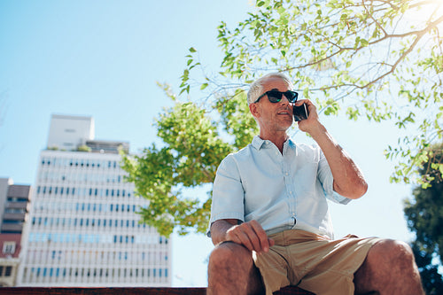 Mature man sitting outdoors talking on cell phone