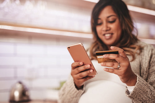 Pregnant woman shopping online with credit card and mobile phone
