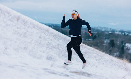 Hillside running takes the woman uphill through winter snow during training