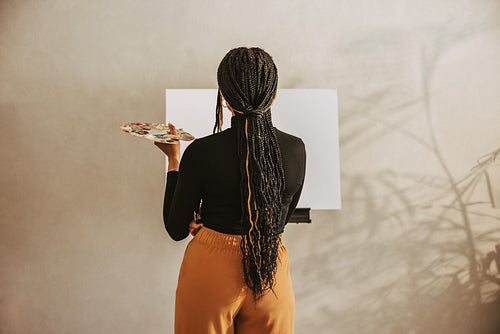 Creative young woman holding a palette in an art studio