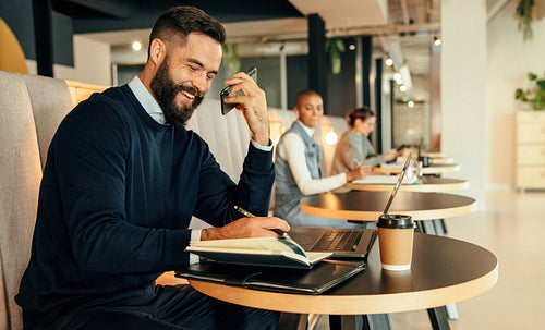 Happy businessman taking a phone call in a co-working space