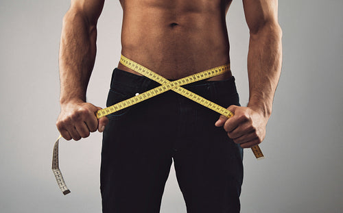 Fitness man measuring his waist