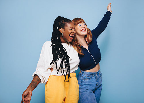 Two cheerful best friends laughing and having fun while embracing each other