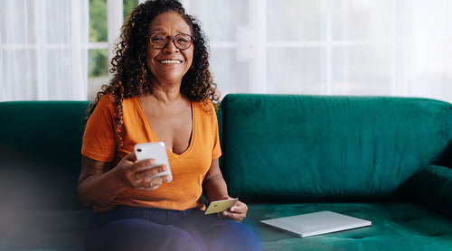 Happy senior woman enjoying an online shopping spree with a smartphone