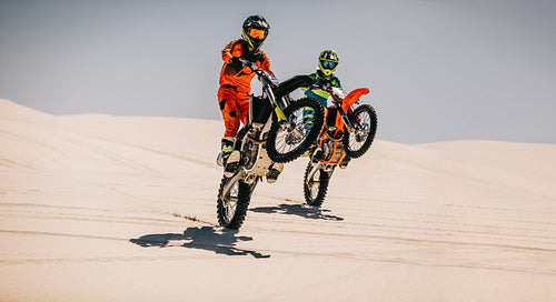Motocross riders doing wheelie together