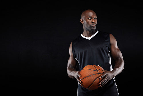 Muscular basketball player on black background