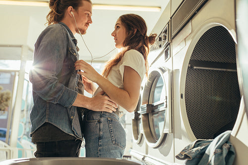 Couple in love standing together listening to music in laundry room