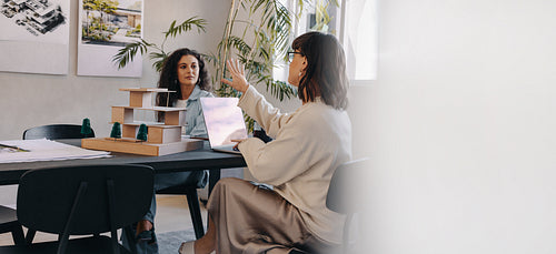 Female professionals discussing project management strategies in modern office setting