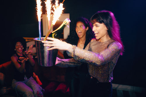 Women celebrating with champagne and sparklers at a vibrant party