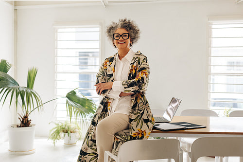 Happy businesswoman sitting on a table in a meeting room