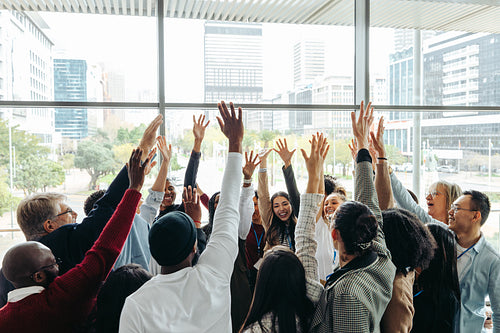 Happy work colleagues showcasing unity with raised hands