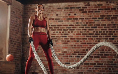 Smiling woman using battle ropes for exercising
