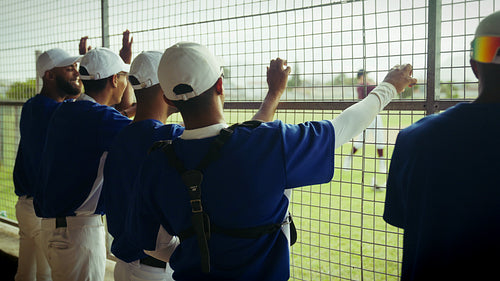 Baseball players watch game action from the dugout