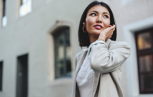Female student listening to a podcast while waiting for a cab
