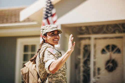 Happy servicewoman waving her hand on her homecoming