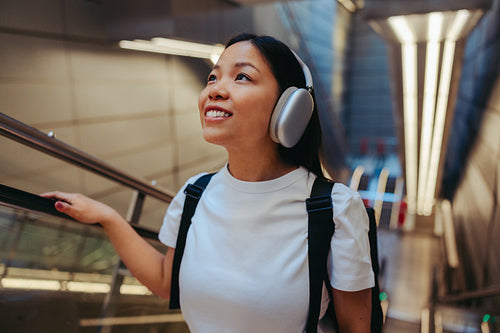 Commuter woman listening with headphones on escalator