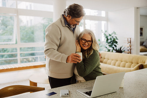 Senior couple uses laptop for online shopping at home