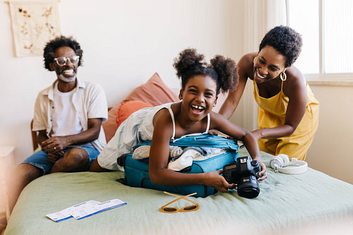 Excited daughter holding camera while travel packing with her parents