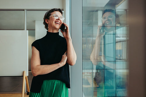 Successful gender-fluid business owner smiling while talking on the phone