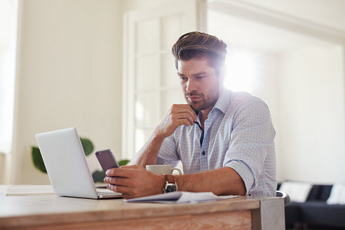 Business man at home office with smart phone and laptop