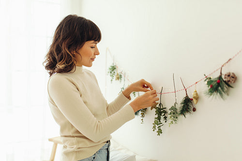 Close up of woman decorating wall with twigs for christmas