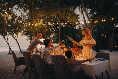 Family toasting to good health during sunset dining on island
