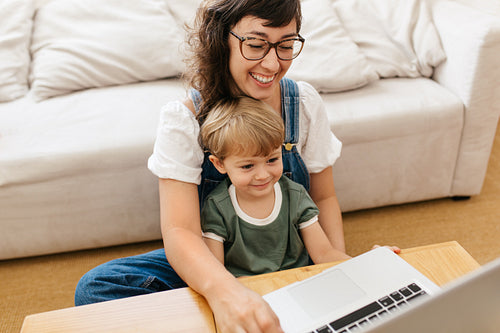Smiling mother and son together using laptop