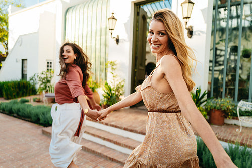 Woman leading her friend by the hand at a holiday resort