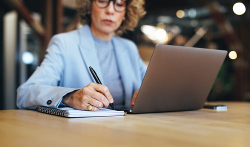 Business woman writes a to do list on a notepad, planning her work week
