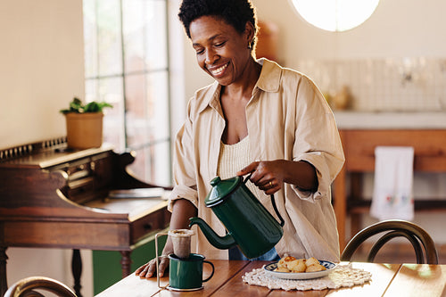 Mature woman pouring filtered coffee and serving a delicious Brazilian breakfast at home