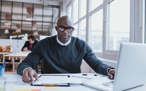 Handsome young african man at his desk with laptop
