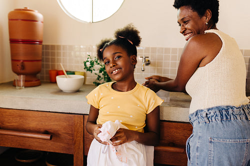 Young girl learning about hygiene and hand washing with her mom