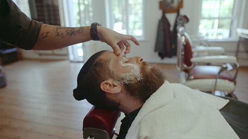 Barber styling the beard of customer