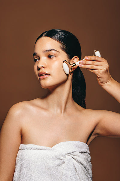 Skincare with a jade roller: Beautiful woman massages her skin with a