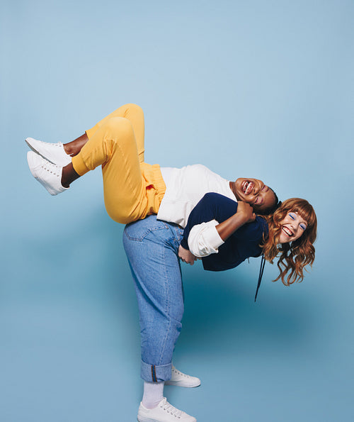 Woman carrying her friend on her back in a studio