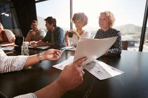 Papers in hands of man explaining plan to creative team