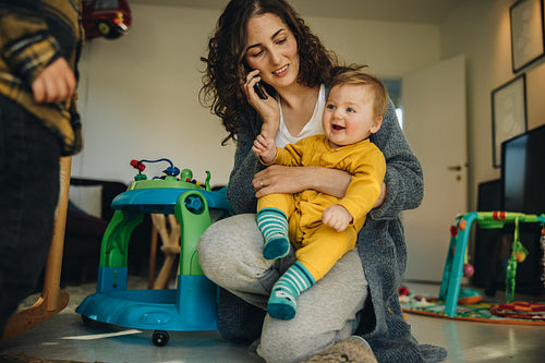 Mother holding baby while talking on phone