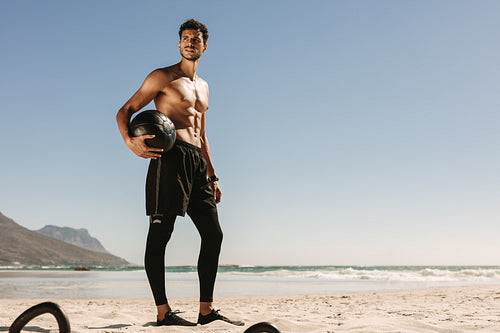 Man doing fitness training at the beach using a medicine ball