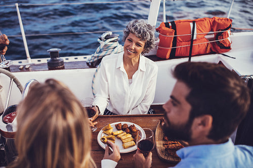 Senior woman with a young couple having meal on the boat