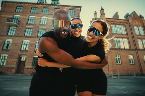 Close friends hugging after group run in urban setting