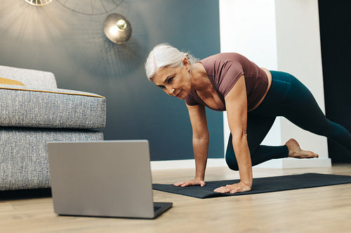 Yoga at home: Woman using laptop to attend virtual yoga session