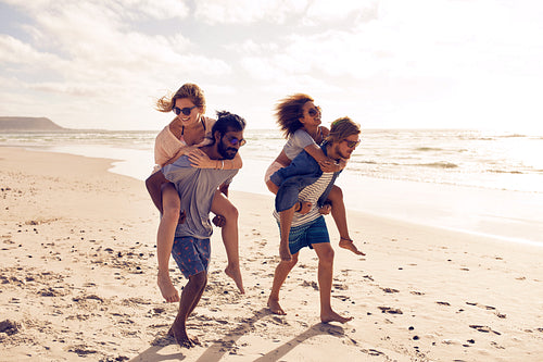 Friends piggyback along the beach