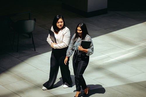 Female colleagues walking together in modern office setting