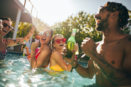 Group of happy friends at pool party with beers