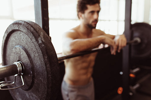 Muscular man leaning over barbell