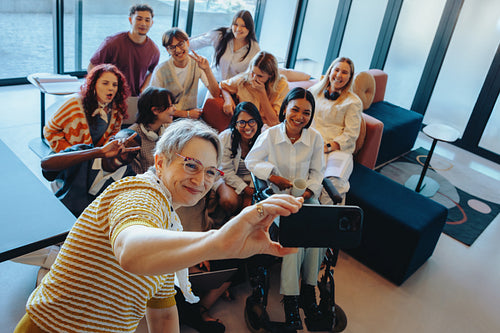Diverse group of university classmates posing together for a selfie indoors, capturing a moment of friendship and inclusion